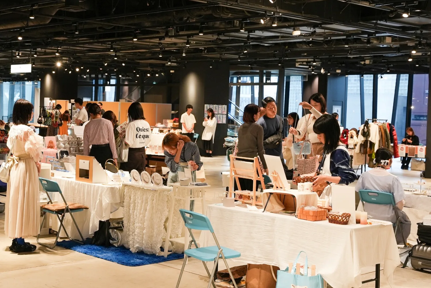 東急プラザ銀座の「馳せる。」会場で、白い展示台を巡りブランドと交流する来場者たち